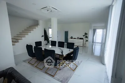 Spacious modern dining room with elegant black chairs and sleek marble table in a bright open-plan layout.