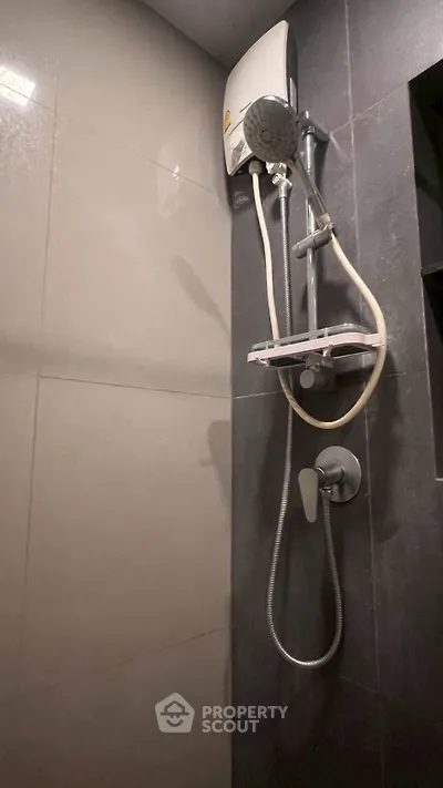 Modern bathroom with sleek shower fixtures and dark tile design.