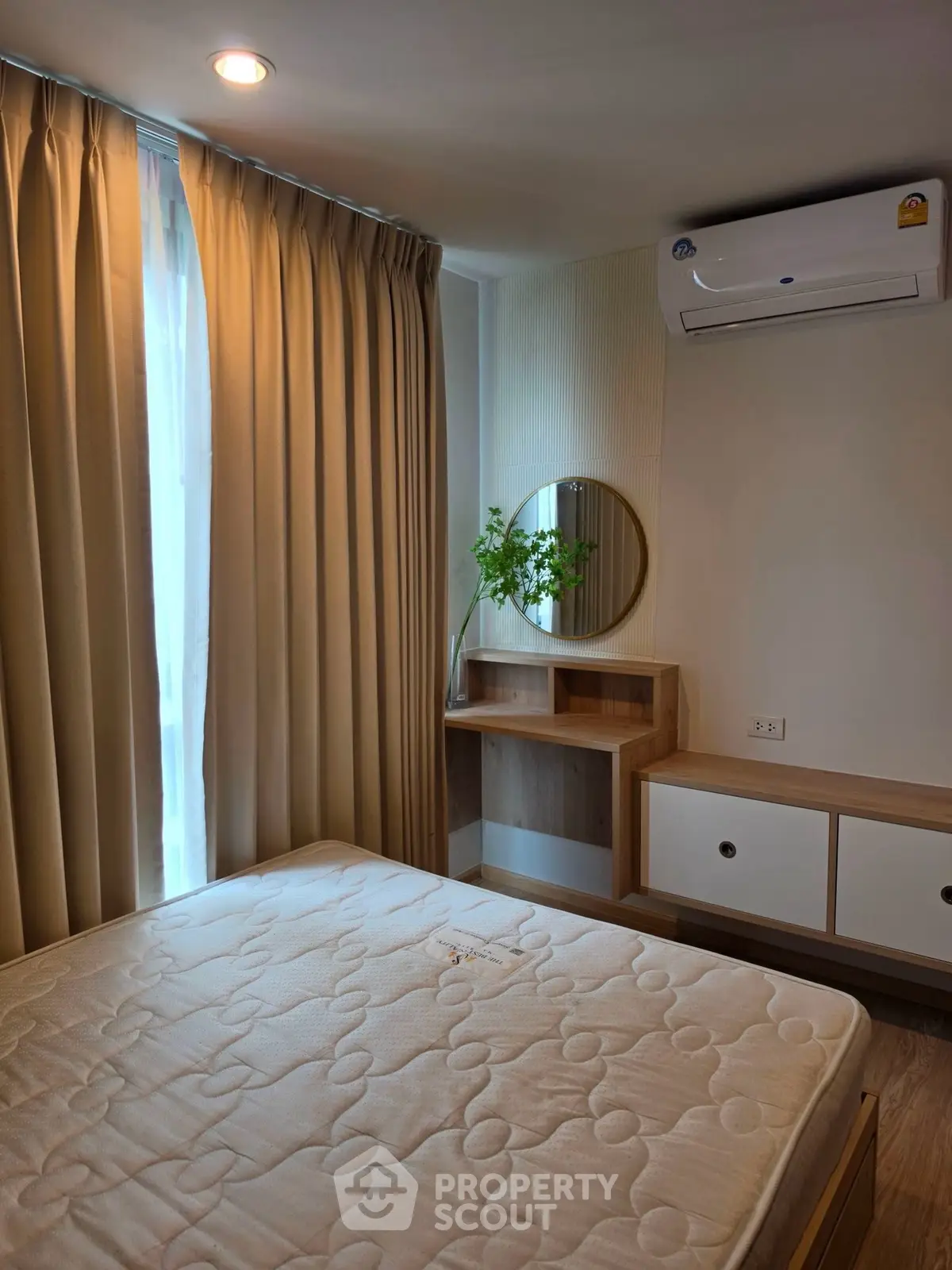 Cozy bedroom with natural light, modern furnishings, and air conditioning unit.