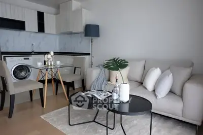 Modern living room with open kitchen, featuring sleek furniture and integrated washing machine.