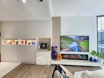 Modern living room with stylish decor and large TV displaying scenic view, featuring sleek built-in storage.