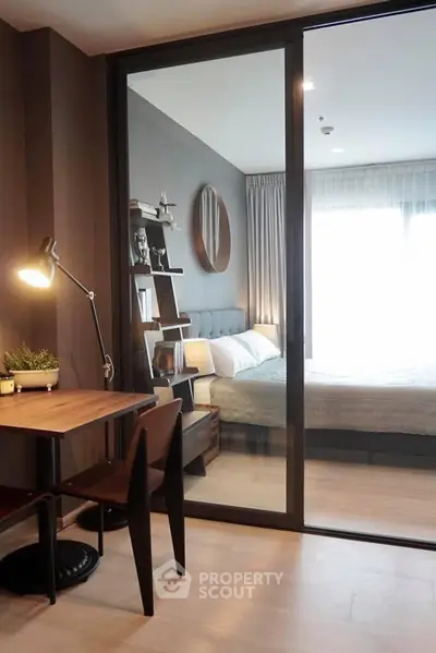 Modern bedroom with stylish decor and study area, featuring natural light and elegant furnishings.