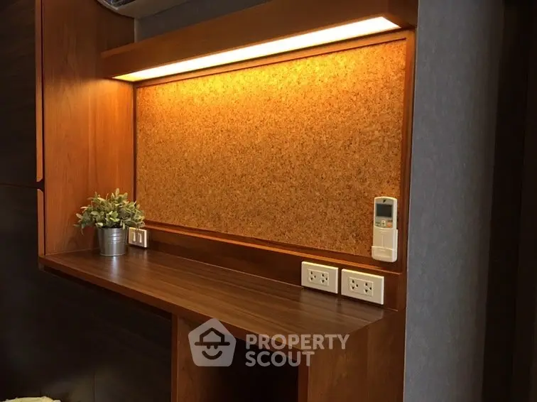 Modern study nook with wooden desk, corkboard, and built-in power outlets in stylish home interior.