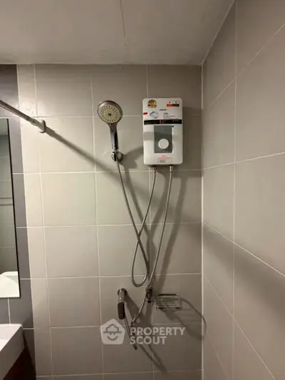 Modern bathroom with sleek showerhead and tiled walls, perfect for a contemporary home.
