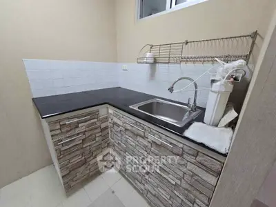 Modern kitchen with sleek black countertop and stone-patterned cabinets, featuring a stainless steel sink and water filter.