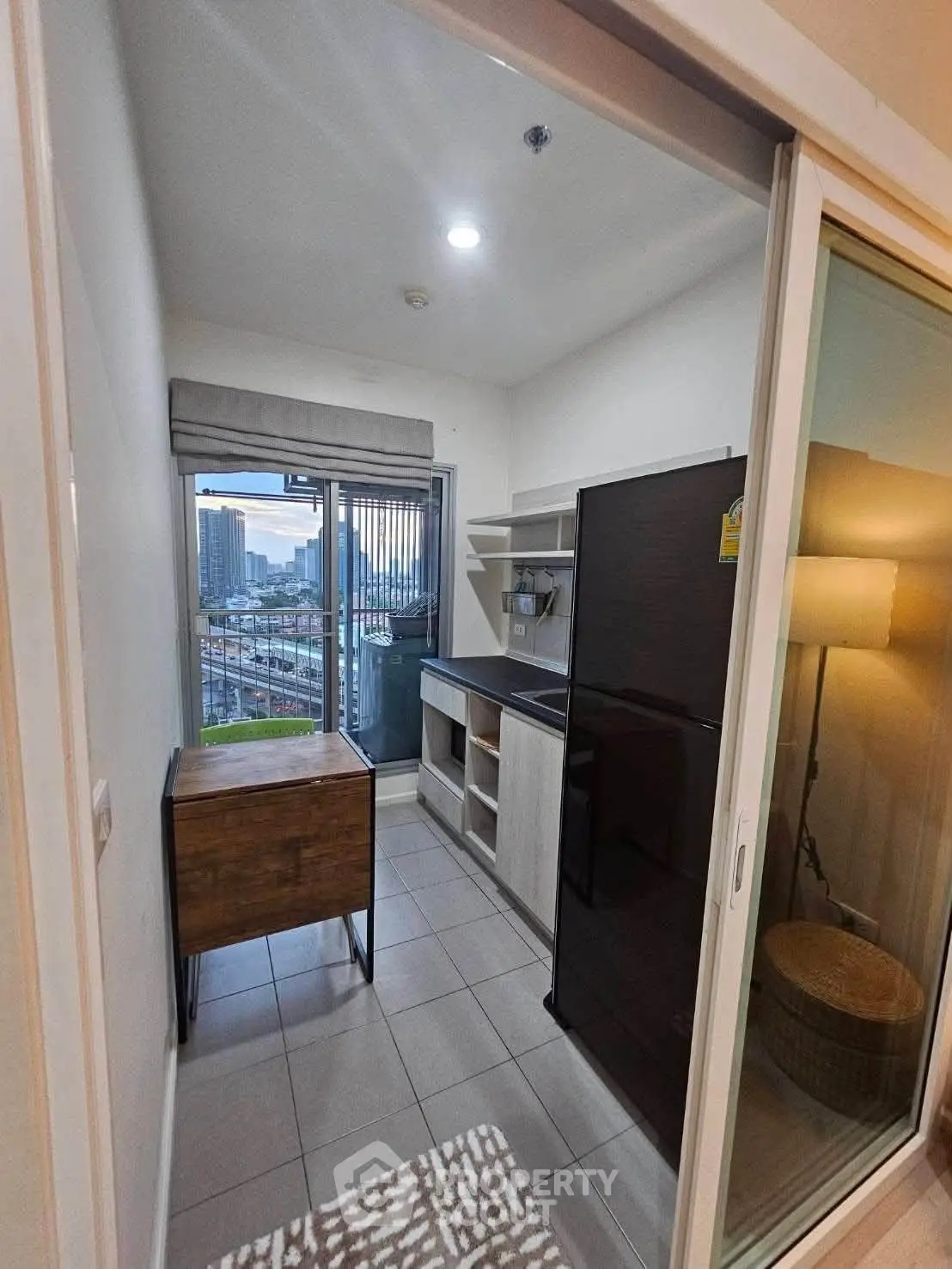 Modern compact kitchen with city view, featuring sleek appliances and ample natural light.