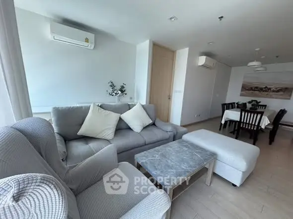 Spacious living room with modern furniture and dining area in open layout apartment.