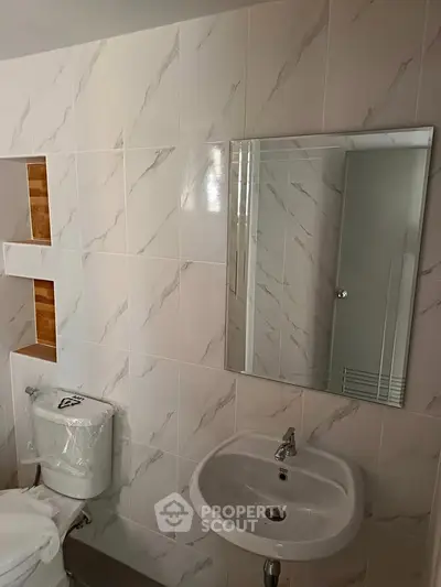 Modern bathroom with sleek white tiles and compact fixtures for a clean, minimalist look.