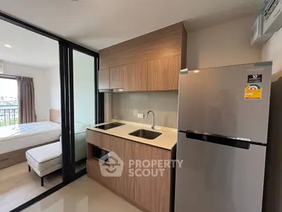 Modern kitchen with sleek cabinetry and stainless steel fridge in a compact apartment setting.