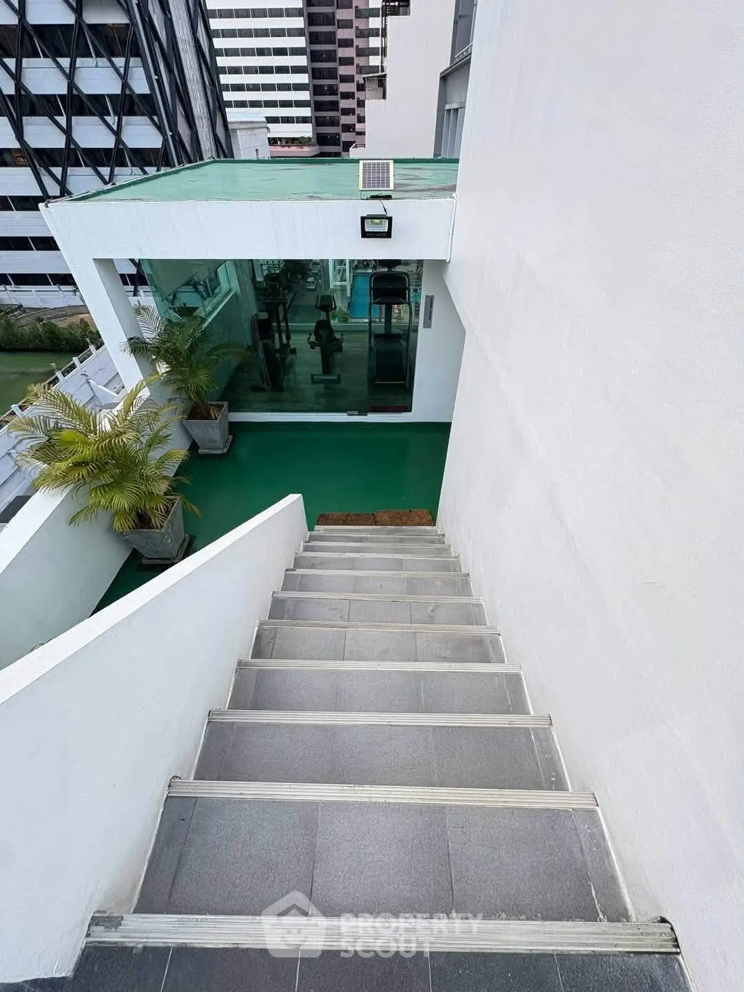 Modern building exterior with staircase leading to gym area, featuring sleek design and urban appeal.