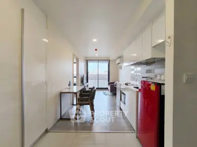 Modern open-plan living room with kitchen and balcony view, featuring sleek furniture and bright natural light.