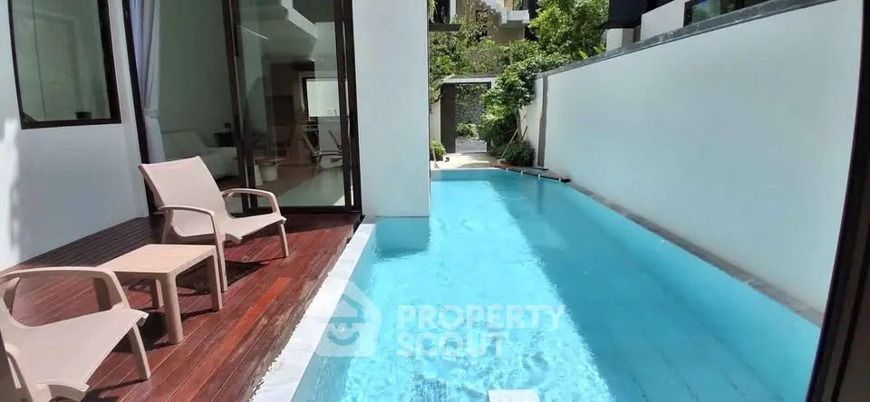 Luxurious private pool with wooden deck and modern seating in a serene outdoor setting.