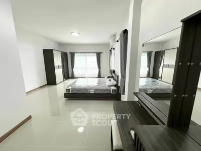 Spacious modern bedroom with sleek furniture and large windows for natural light.