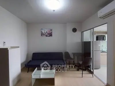Modern living room with sleek furniture and adjacent kitchen area.