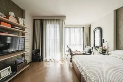 Spacious bedroom with modern decor and large windows offering natural light.