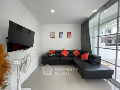 Modern living room with sleek black leather sofa and wall-mounted TV