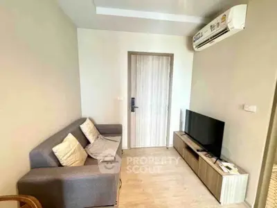 Cozy living room with modern sofa and flat-screen TV, perfect for relaxation.