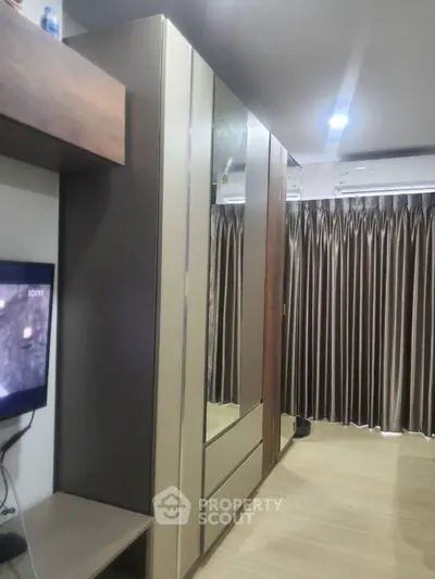Modern bedroom with sleek wardrobe and elegant curtains, featuring a cozy ambiance.