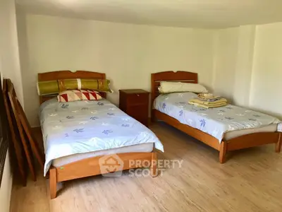 Spacious bedroom with twin beds and wooden furniture, perfect for cozy living.