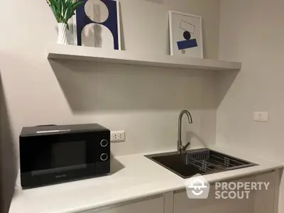 Modern kitchen corner with sleek countertop and microwave, ideal for compact living spaces.