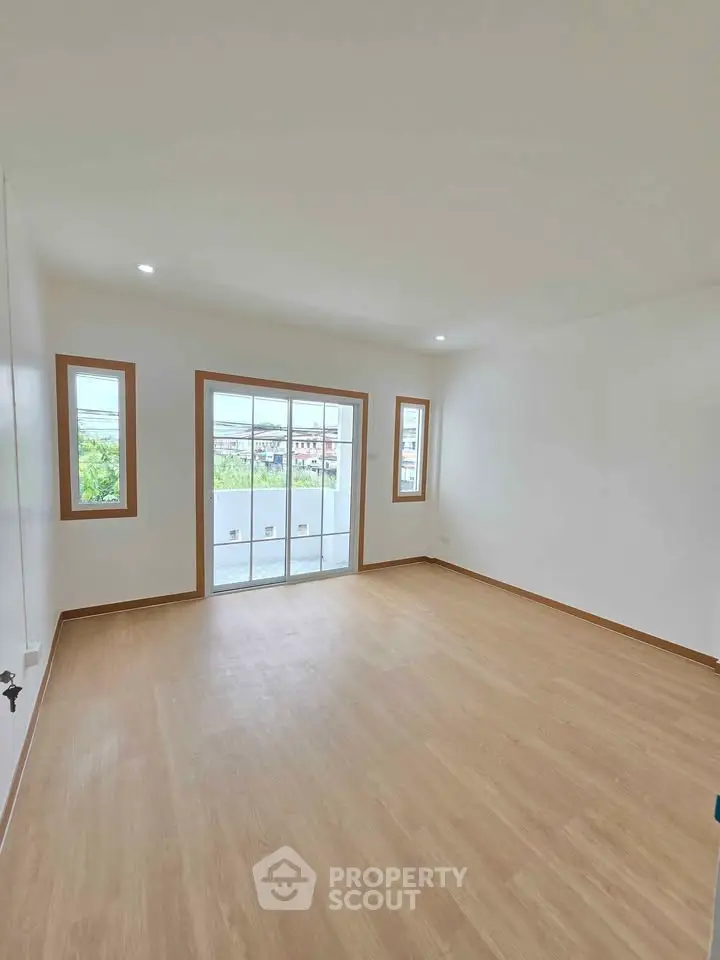 Spacious empty room with large windows and wooden flooring, ideal for customization.