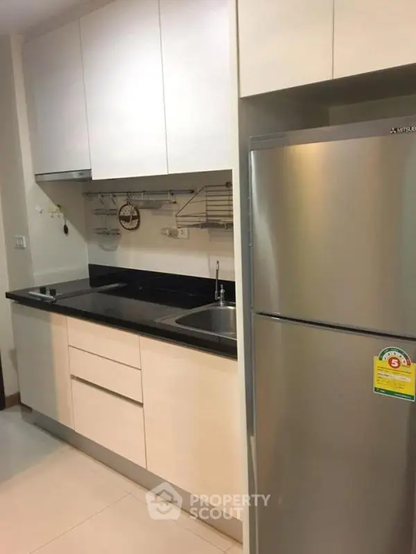 Modern kitchen with sleek cabinetry and stainless steel fridge in a stylish apartment.