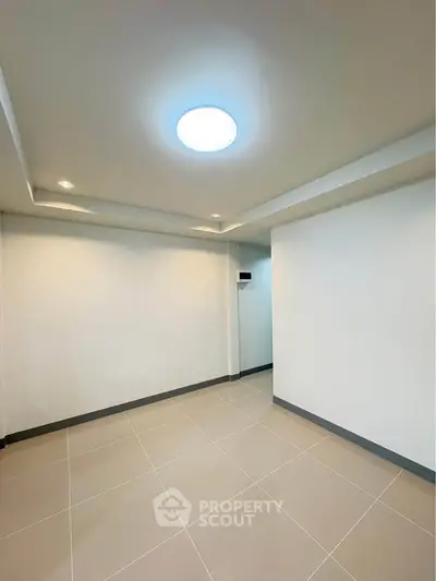 Spacious empty room with modern ceiling lights and tiled flooring, ideal for customization.