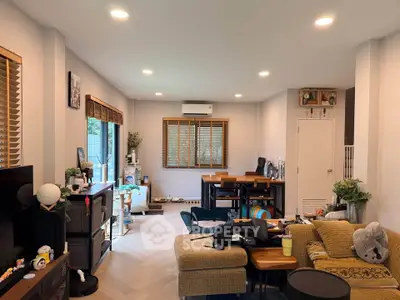 Spacious living room with modern decor and ample natural light, featuring cozy seating and dining area.