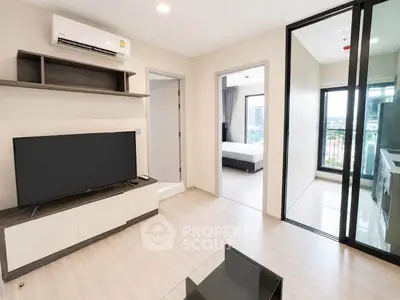 Modern living room with sleek TV unit and view into bedroom and kitchen