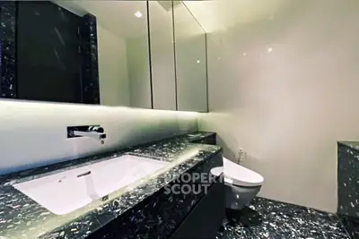 Luxurious modern bathroom with sleek black marble countertops and elegant fixtures.