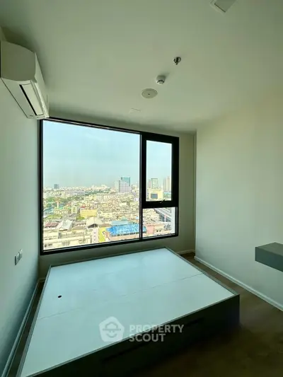Modern bedroom with large window offering stunning city view, featuring minimalist design and air conditioning.