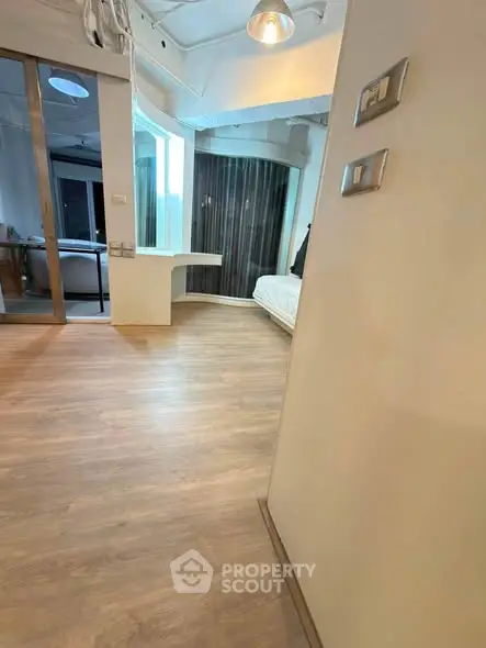 Modern apartment interior with wooden flooring and stylish lighting, featuring a cozy bedroom area.