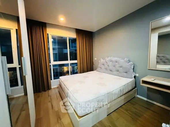 Modern bedroom with plush headboard and large window in stylish apartment.