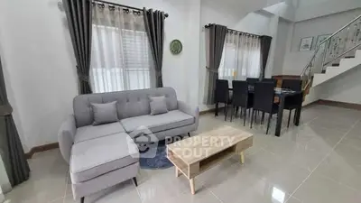 Spacious modern living room with elegant gray sofa and dining area, perfect for family gatherings.
