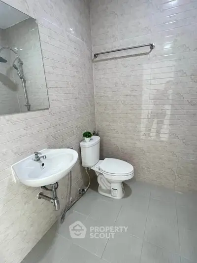 Modern bathroom with sleek fixtures and tiled walls, featuring a toilet and sink.
