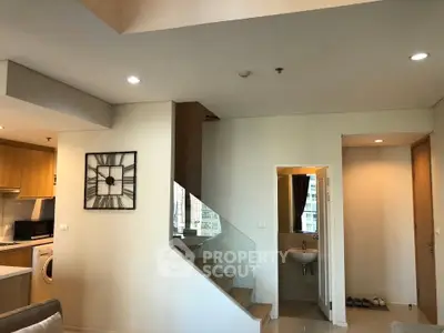 Modern duplex apartment interior with stylish staircase and open kitchen layout.