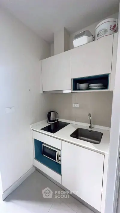 Modern compact kitchen with sleek white cabinetry and built-in appliances