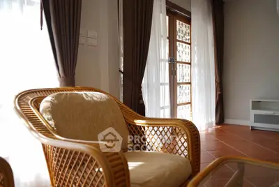 Charming living room with natural light, featuring elegant wicker furniture and floor-to-ceiling windows.