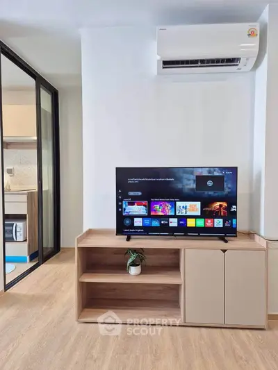 Modern living room with TV, air conditioning, and stylish wooden furniture in a cozy apartment.