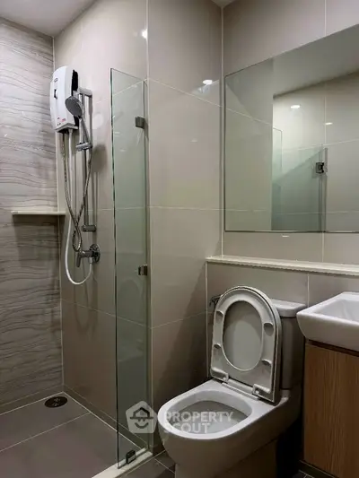Modern bathroom with glass shower and sleek fixtures in contemporary apartment.