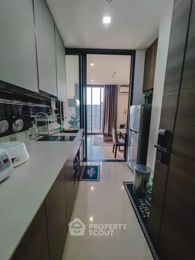 Modern kitchen with sleek cabinetry and open layout leading to dining area with city view.