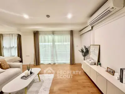 Spacious living room with modern decor and natural light, featuring a cozy seating area and stylish furnishings.