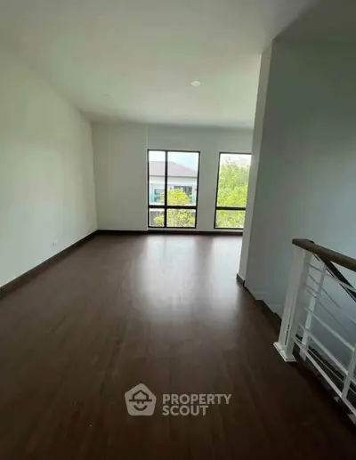 Spacious room with large windows and wooden flooring, perfect for a cozy living area.