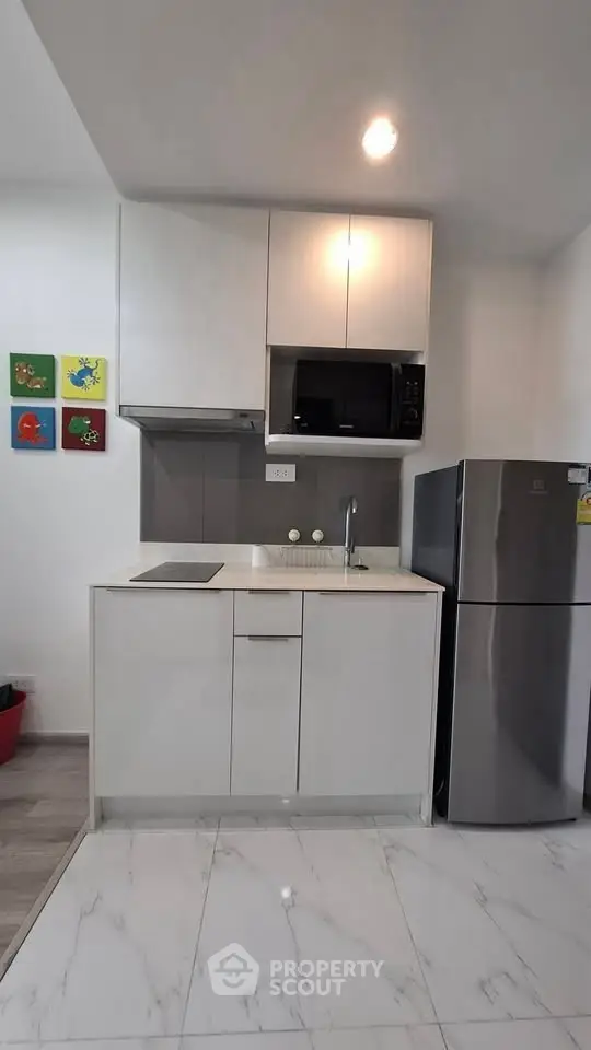 Modern compact kitchen with sleek appliances and colorful wall art