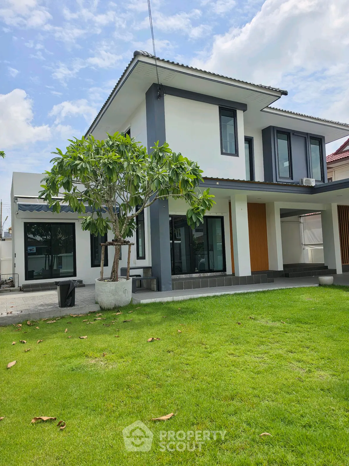 Modern two-story house with lush green lawn and contemporary design.