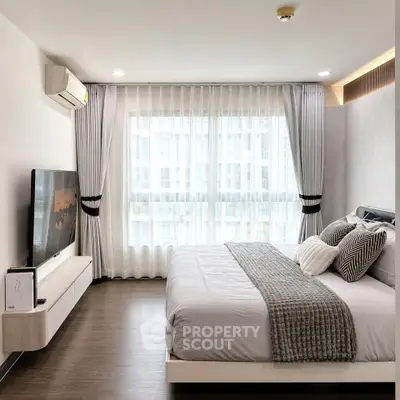 Modern bedroom with large window and stylish decor in a contemporary apartment.