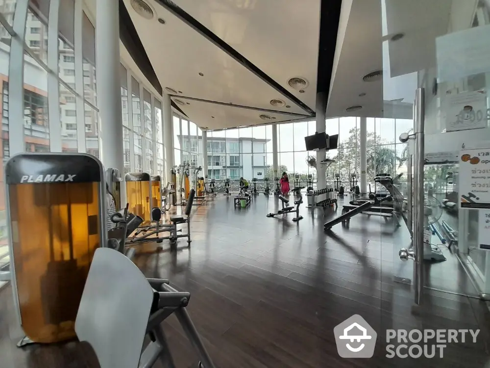 Spacious modern gym with large windows and state-of-the-art equipment in luxury residential building.