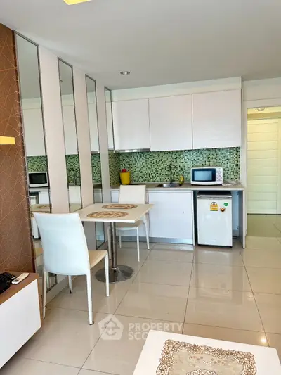 Modern kitchen with sleek white cabinets and mosaic backsplash in a cozy apartment.