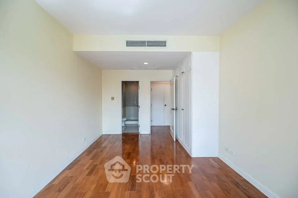 Spacious empty room with wooden flooring and built-in closet