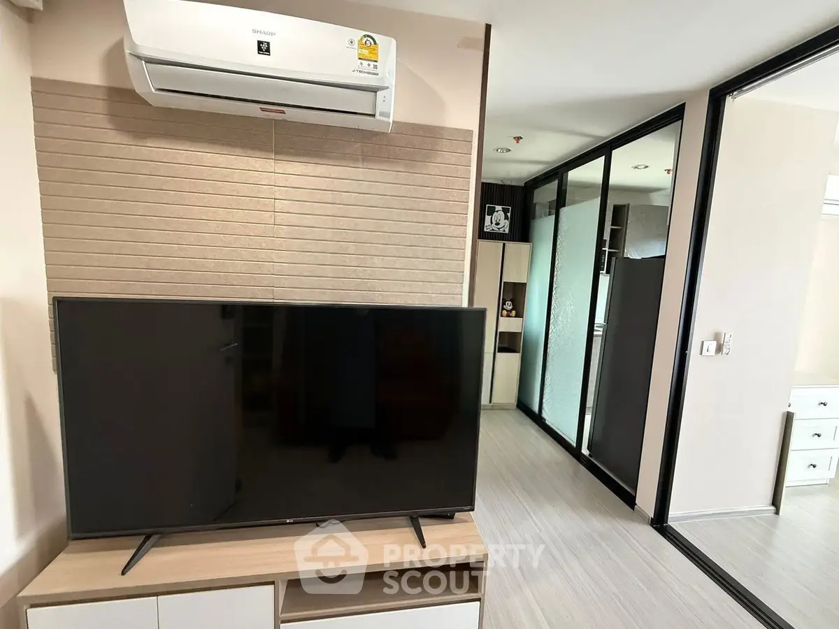 Modern living room with sleek TV setup and air conditioning in a stylish apartment.